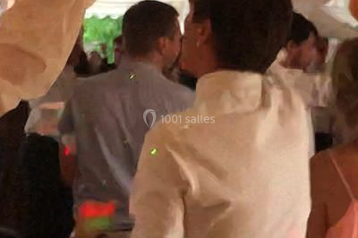 Une femme en robe blanche joue de la harpe dans une salle décorée avec des plantes et des lumières.