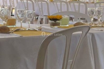 Une femme en robe blanche joue de la harpe dans une salle décorée avec des plantes et des lumières.