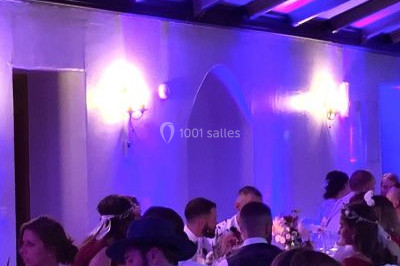 Une femme en robe blanche joue de la harpe dans une salle décorée avec des plantes et des lumières.
