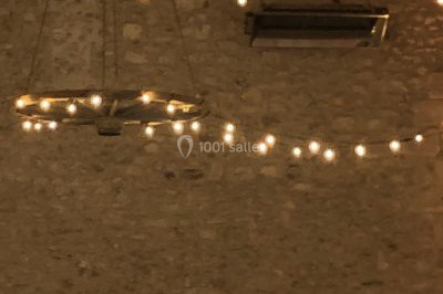 Une femme en robe blanche joue de la harpe dans une salle décorée avec des plantes et des lumières.