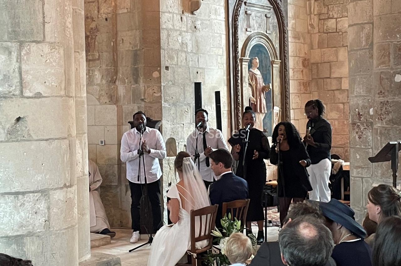 Un groupe de chanteurs interprète un morceau lors d'une cérémonie de mariage dans une église en pierre.