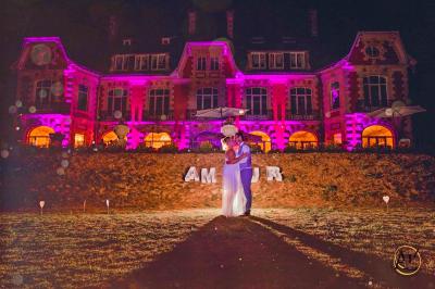 Une femme en robe blanche joue de la harpe dans une salle décorée avec des plantes et des lumières.