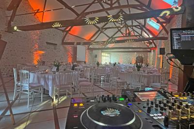 Une femme en robe blanche joue de la harpe dans une salle décorée avec des plantes et des lumières.