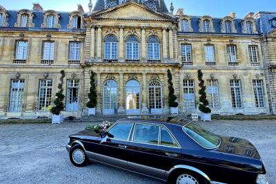 Une femme en robe blanche joue de la harpe dans une salle décorée avec des plantes et des lumières.