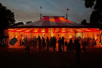 Une femme en robe blanche joue de la harpe dans une salle décorée avec des plantes et des lumières.