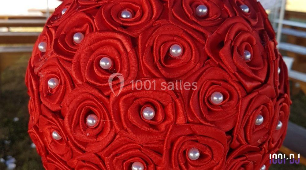Bouquet sphérique composé de roses rouges en tissu ornées de perles blanches au centre.