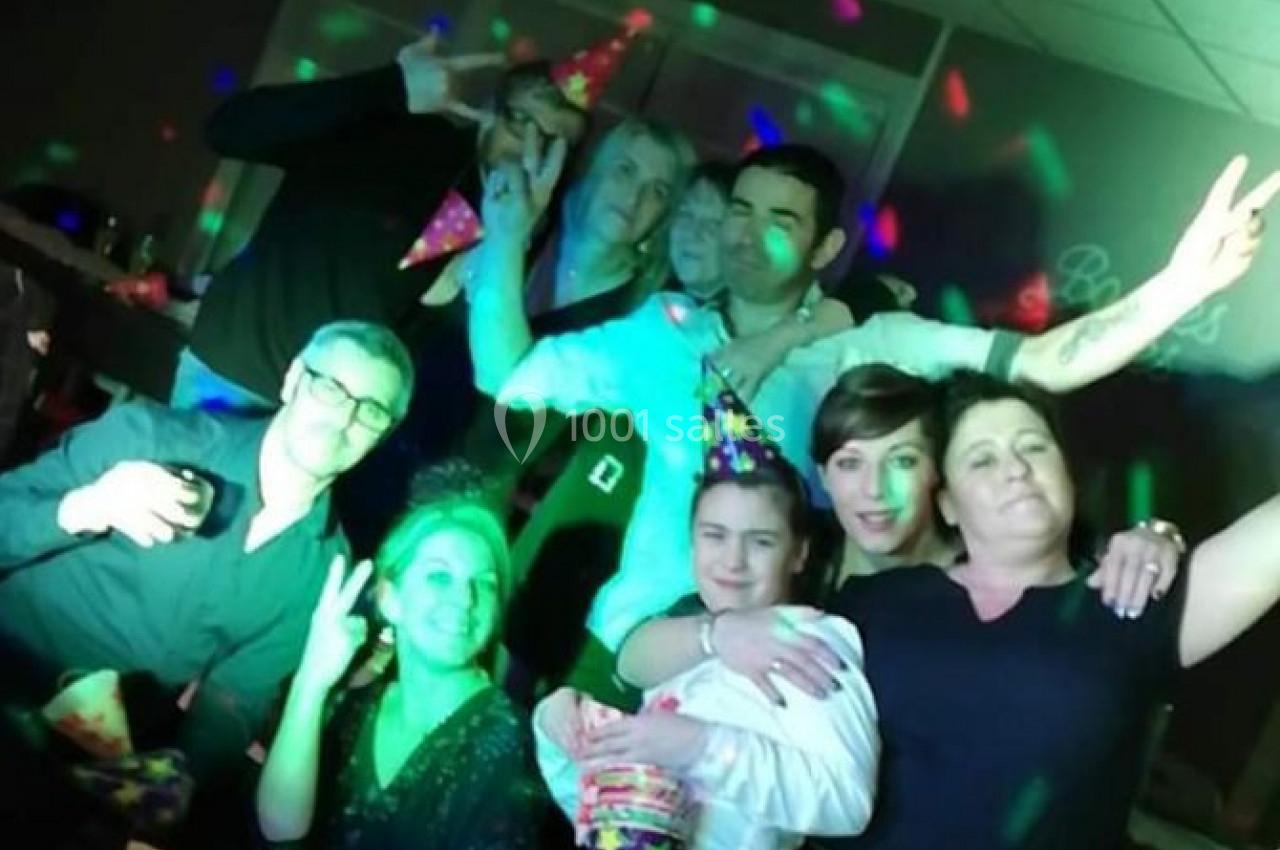 Un groupe de personnes posant joyeusement dans une ambiance festive avec des lumières colorées.