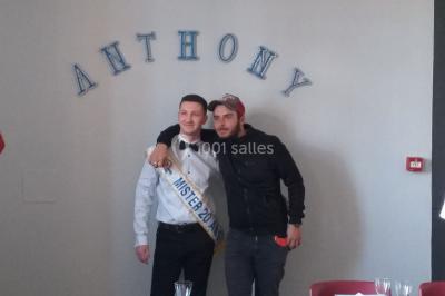 Deux mains entrelacées sur une table, avec des verres et une ambiance romantique en arrière-plan.