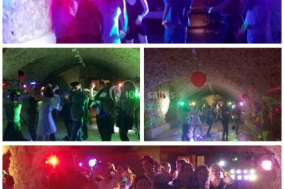 Deux mains entrelacées sur une table, avec des verres et une ambiance romantique en arrière-plan.