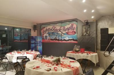 Deux mains entrelacées sur une table, avec des verres et une ambiance romantique en arrière-plan.