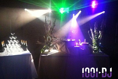 Salle de réception décorée avec des tables rondes dressées, des nappes blanches et des éclairages bleutés.