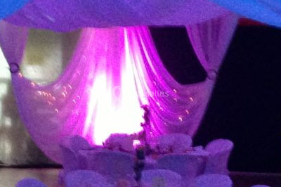 Salle de réception décorée avec des tables rondes dressées, des nappes blanches et des éclairages bleutés.