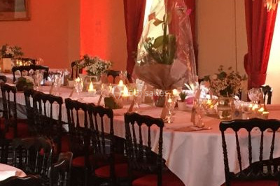 Salle de réception décorée avec des tables rondes dressées, des nappes blanches et des éclairages bleutés.