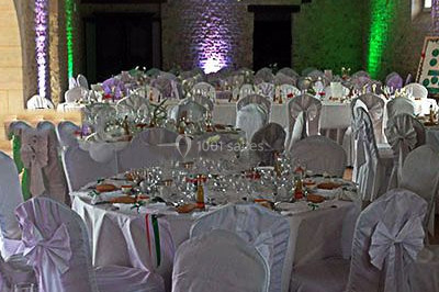 Salle de réception décorée avec des tables rondes dressées, des nappes blanches et des éclairages bleutés.