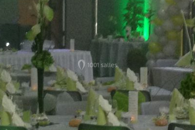 Salle de réception décorée avec des tables rondes dressées, des nappes blanches et des éclairages bleutés.
