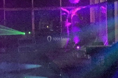 Salle de réception décorée avec des tables rondes dressées, des nappes blanches et des éclairages bleutés.