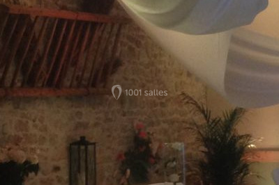 Salle de réception décorée avec des tables rondes dressées, des nappes blanches et des éclairages bleutés.