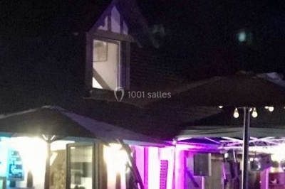 Salle de réception décorée avec des tables rondes dressées, des nappes blanches et des éclairages bleutés.