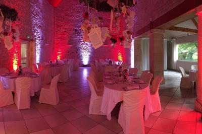 Salle de réception décorée avec des tables rondes dressées, des nappes blanches et des éclairages bleutés.