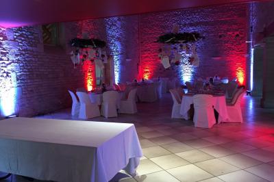 Salle de réception décorée avec des tables rondes dressées, des nappes blanches et des éclairages bleutés.