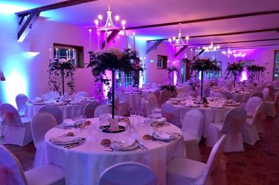 Salle de réception décorée avec des tables rondes dressées, des nappes blanches et des éclairages bleutés.