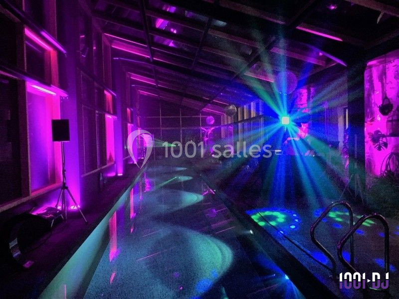 Piscine intérieure éclairée par des lumières colorées et effets lumineux, créant une ambiance festive.