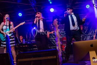Scène de concert avec instruments et éclairages colorés dans une salle vide.