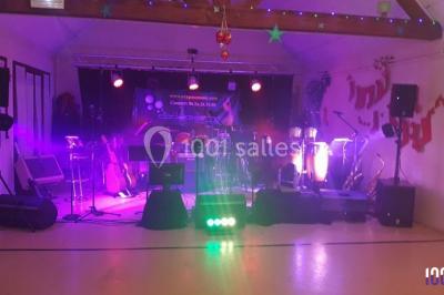 Scène de concert avec instruments et éclairages colorés dans une salle vide.