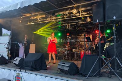 Scène de concert avec instruments et éclairages colorés dans une salle vide.