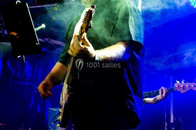 Scène de concert avec instruments et éclairages colorés dans une salle vide.