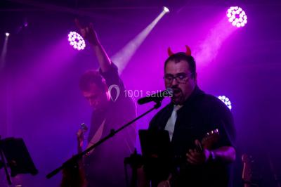 Scène de concert avec instruments et éclairages colorés dans une salle vide.