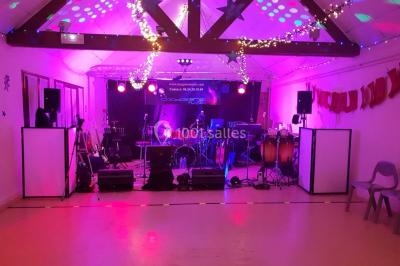 Scène de concert avec instruments et éclairages colorés dans une salle vide.