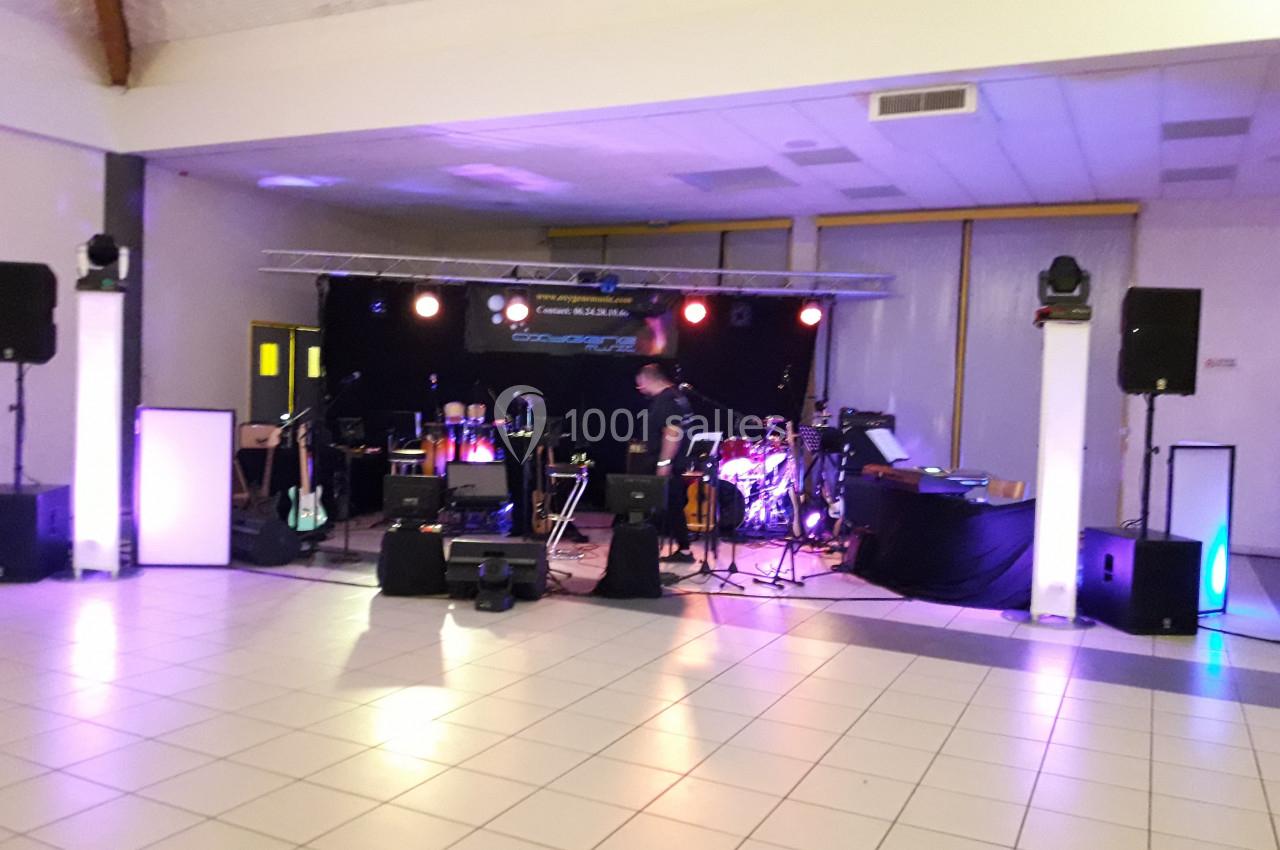 Scène de concert avec instruments et éclairages colorés dans une salle vide.