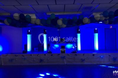 Scène équipée de matériel de sonorisation et d'éclairage, avec une table de mixage et des projecteurs bleus.