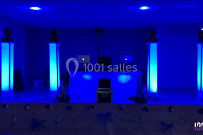 Scène équipée de matériel de sonorisation et d'éclairage, avec une table de mixage et des projecteurs bleus.