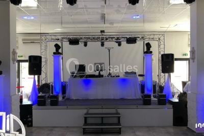 Scène équipée de matériel de sonorisation et d'éclairage, avec une table de mixage et des projecteurs bleus.