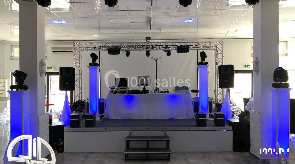 Scène équipée de matériel de sonorisation et d'éclairage, avec une table de mixage et des projecteurs bleus.