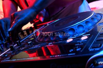 Groupe de personnes réunies en soirée en plein air, éclairées par des guirlandes lumineuses et des lampadaires.