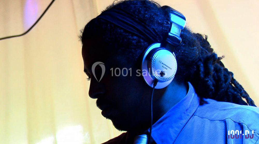 Un DJ portant un casque audio, concentré, éclairé par une lumière bleue sur un fond jaune.