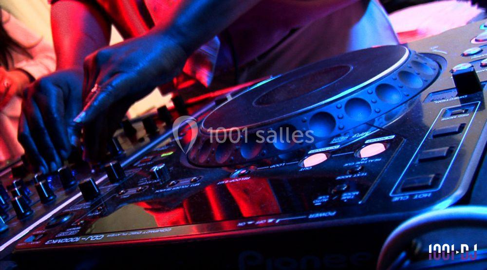 Un DJ mixant de la musique sur une table de mixage éclairée par des lumières colorées.