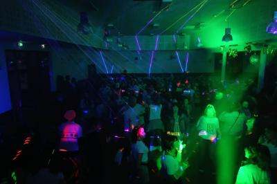 Groupe de personnes réunies en soirée en plein air, éclairées par des guirlandes lumineuses et des lampadaires.