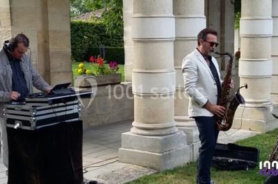 Des personnes dansent sous des lumières rouges dans une salle ornée de décorations murales et de lustres.