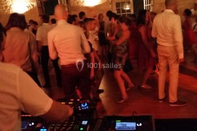 Des personnes dansent sous des lumières rouges dans une salle ornée de décorations murales et de lustres.