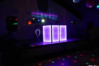 Un homme chante au micro sur une scène éclairée par des lumières bleues et violettes.