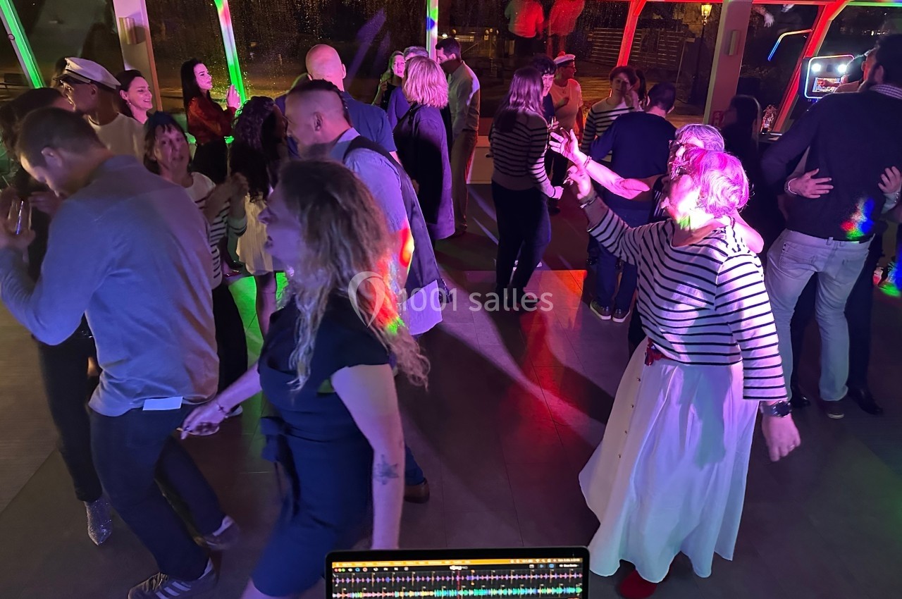 Personnes dansant et socialisant sur une piste éclairée par des lumières colorées dans une ambiance festive.