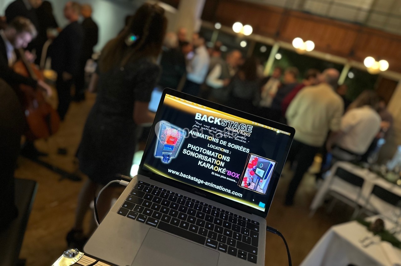 Ordinateur portable affichant une page de services événementiels, posé dans une salle avec des personnes en arrière-plan…