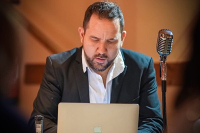 Borne de karaoké avec écran tactile affichant une interface de sélection de chansons, dans une salle animée.