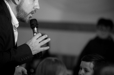 Borne de karaoké avec écran tactile affichant une interface de sélection de chansons, dans une salle animée.