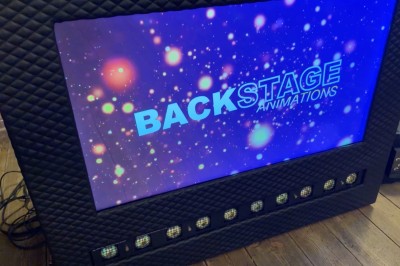 Borne de karaoké avec écran tactile affichant une interface de sélection de chansons, dans une salle animée.