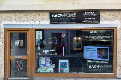 Borne de karaoké avec écran tactile affichant une interface de sélection de chansons, dans une salle animée.